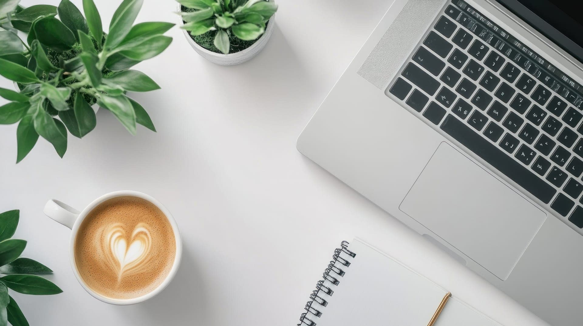 Rustige werkplek met een laptop, een kop latte, een notitieboek en een groene plant - een huiselijke plek om rustig je geldzaken te regelen
